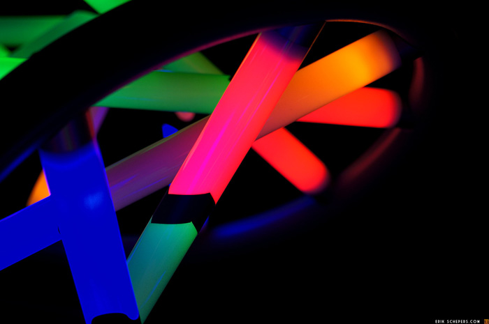 Closeup photo of DNA structure model with base pairs represented by glowing neon bars.